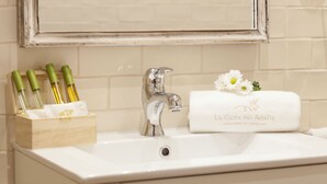 A bathroom sink with a mirror above it, a towel with a flower, and a wooden box with bottles. - El Envero en La Casa del Aceite (Cordoba)