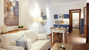 Una sala de estar acogedora con un sof á, una mesa de comedor y una cocina al fondo.