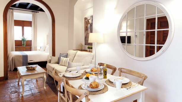 Una habitación acogedora con cama, zona de estar y mesa de comedor dispuesta para el desayuno.