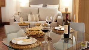 A dining table with a bottle of wine, two wine glasses, and a woven basket.