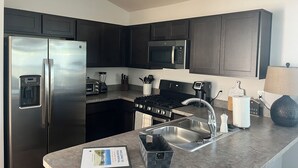 A modern kitchen with dark cabinets, stainless steel appliances, a built-in microwave, and a gas stove. - The Sunshine Retreat in the Villages with Golf Car (The Villages)