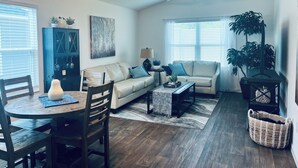A living room with a sofa, coffee table, and dining area with chairs. - The Sunshine Retreat in the Villages with Golf Car (The Villages)