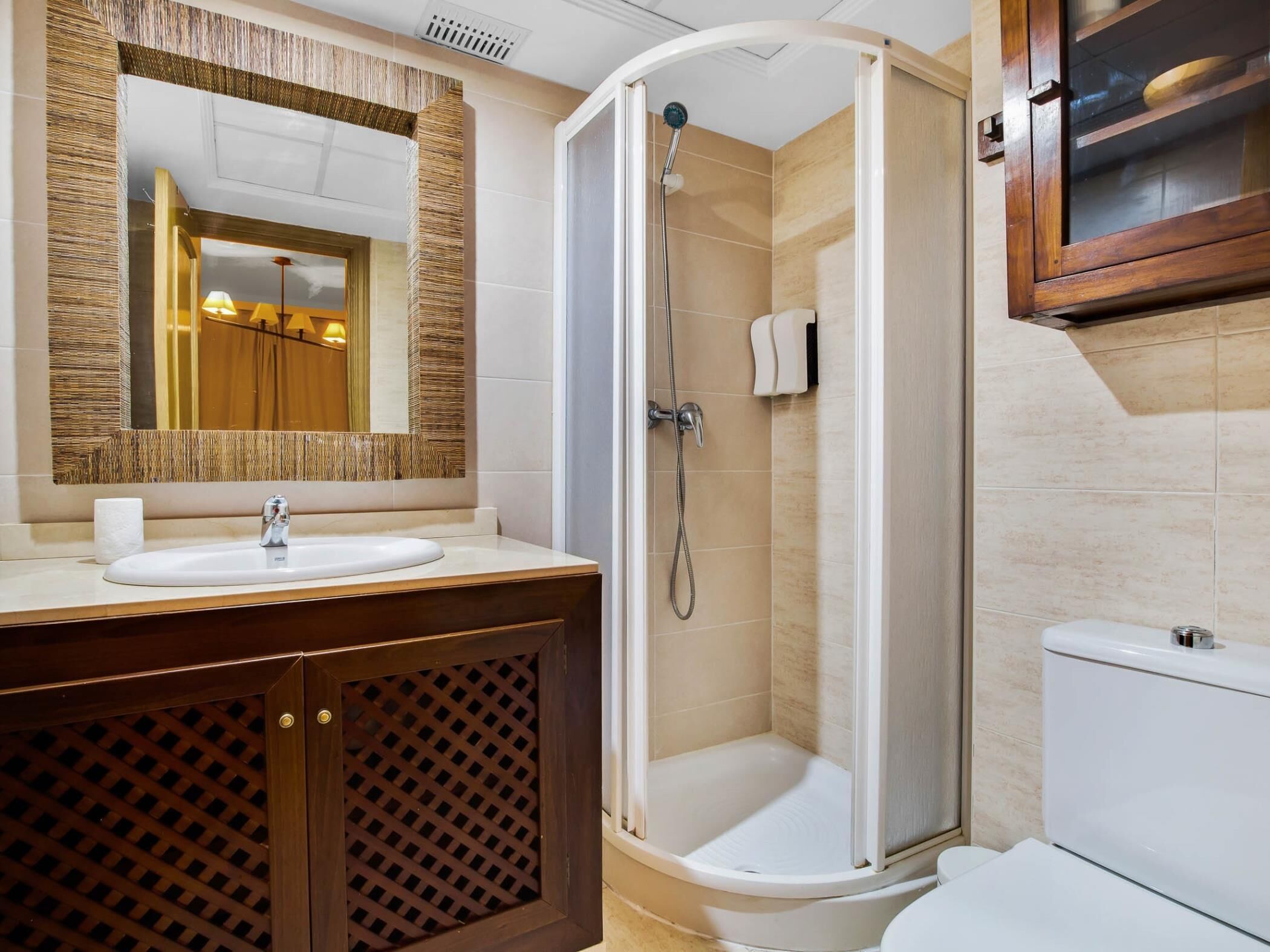 A bathroom with a shower, toilet, sink, and a mirror.
