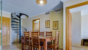 A dining area with a wooden table and chairs, a spiral staircase, and framed artwork on the walls. - Marysol 32 - Penthouse in Benalmádena with swimming pool, 2 terraces, garage (Benalmádena)