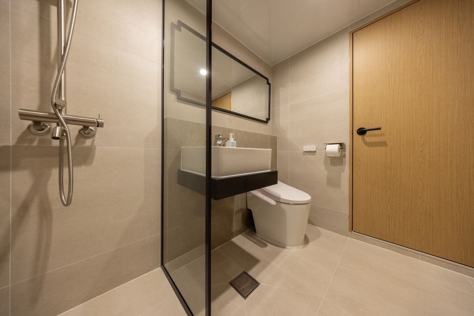 Une salle de bain moderne avec une douche à parois de verre, un lavabo blanc et des toilettes.