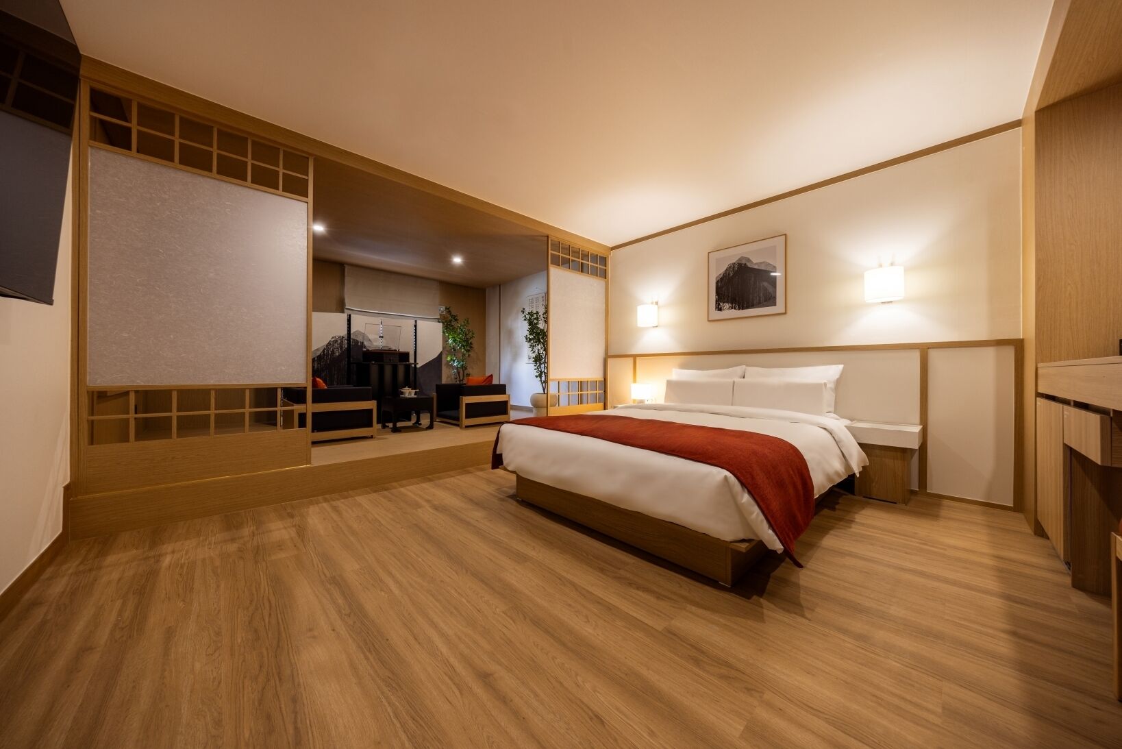 A modern hotel room with a large bed, a desk, and a seating area.