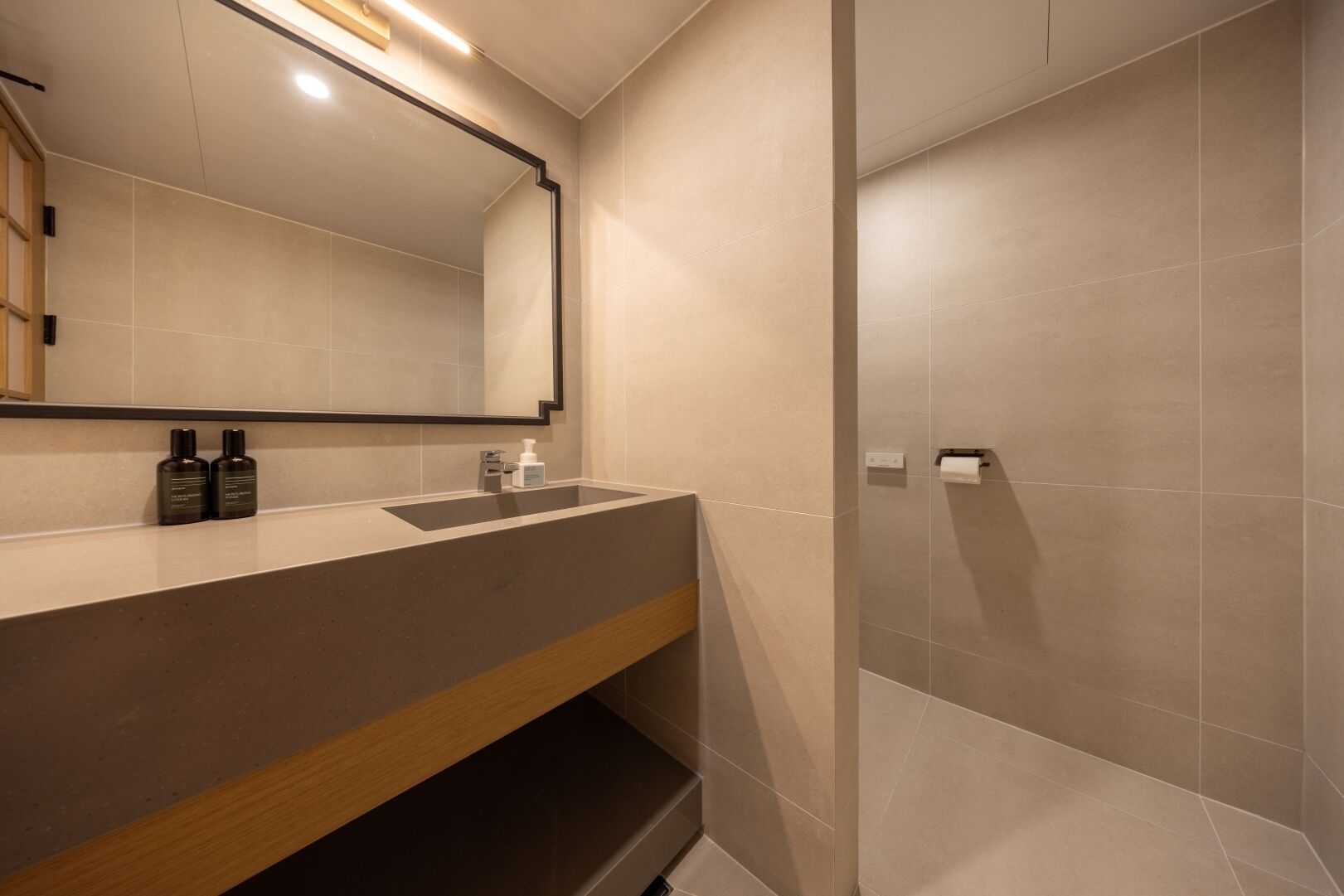 Un baño moderno con un espejo grande, un lavamanos y una zona de ducha.