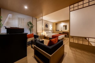 Quarto de hotel com cama, escrivaninha, sofá e uma pequena mesa.