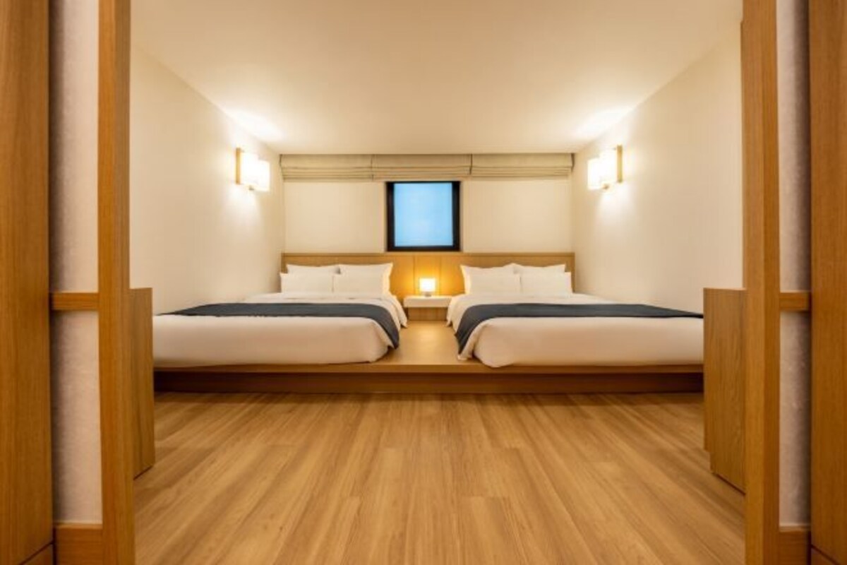 Habitación con dos camas, piso de madera y lámparas de noche.