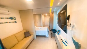 Ein Hotelzimmer mit Sofa, Bett, Schreibtisch mit Computer und Fernseher.