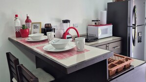A compact kitchen with a dining area, including a microwave, refrigerator, and a small sink.
