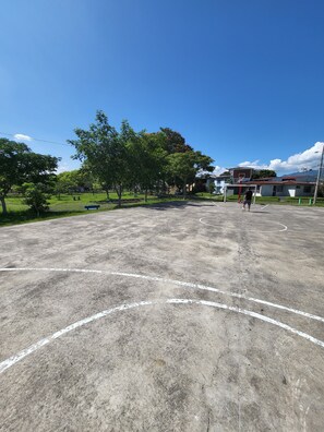 An outdoor basketball court with trees and houses in the background. - BnB Eco Stay (San José)