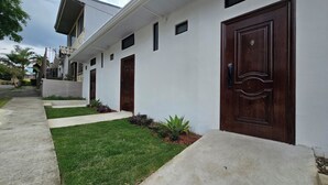 A modern building with a white facade, multiple doors, and a well-maintained lawn.