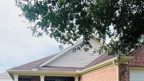 A residential house with a brick exterior, a front porch, and a well-maintained lawn. - Three bedroom home, pets allowed.  (Cypress)