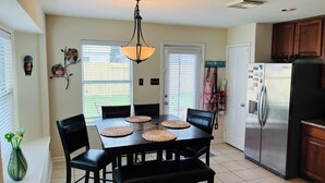 A modern kitchen with a dining table, chairs, and a refrigerator. - Three bedroom home, pets allowed.  (Cypress)