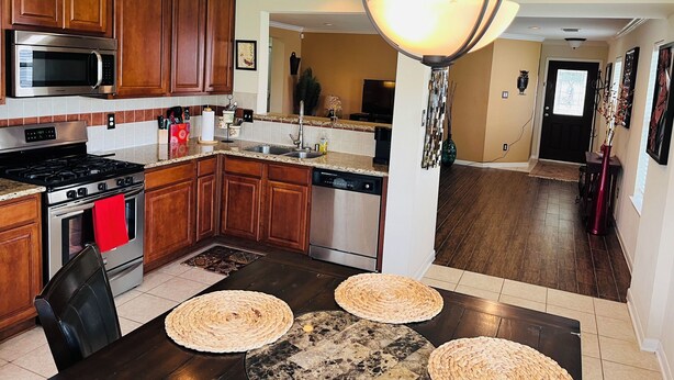 A modern kitchen with wooden cabinets, stainless steel appliances, and a central island. - Three bedroom home, pets allowed.  (Cypress)