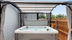 Un jacuzzi con toldo, cerca de madera y terraza de madera.