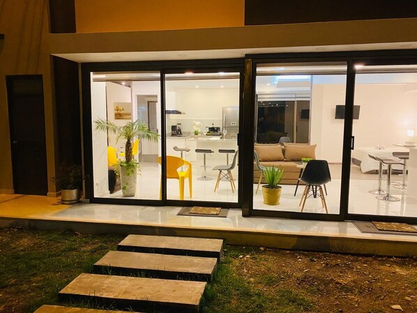 A modern house with a glass door entrance, a kitchen with bar stools, a dining area with a table and chairs, and a living room with a sofa and a coffee table. - Alba de las Sierras (Cuenca)