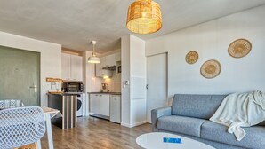 Ein modernes Wohnzimmer mit grauem Sofa, einem weißen Couchtisch und einer Korbtrophäe als Pendelleuchte.