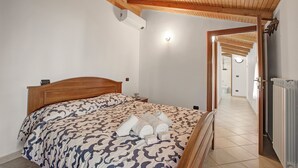Un dormitorio con cabecera de madera, colcha estampada y cama bien tendida con toallas.