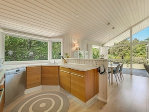 A modern kitchen with a large window, wooden cabinets, and a dining area with a table and chairs.