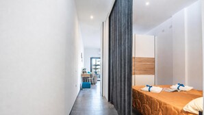 A modern hotel room with a bed, a desk, and a chair.