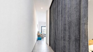 A narrow hallway with a grey textured wall on one side and a white wall on the other.