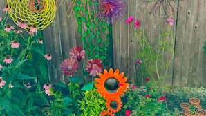 A garden with various flowers and a wooden fence in the background.