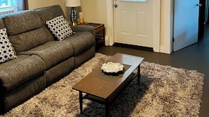 A living room with a sofa, a coffee table, a lamp, and a door with a window.