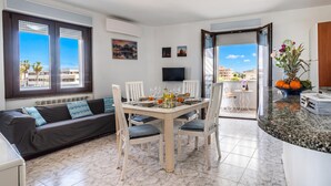 Ein modernes Wohnzimmer mit einer Couch, einem Esstisch, Stühlen, einem Flachbildfernseher und einem Balkon mit Blick.