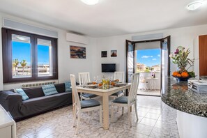 Ein modernes Wohnzimmer mit einer Couch, einem Esstisch, Stühlen, einem Flachbildfernseher und einem Balkon mit Blick.