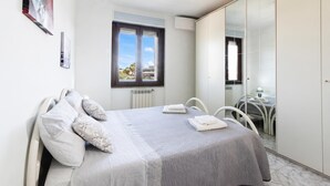 Ein Schlafzimmer mit Bett, Fenster, Stuhl und Kleiderschrank.