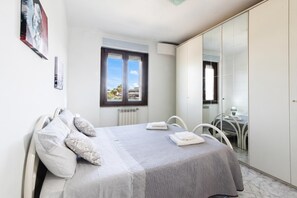 A bedroom with a bed, a window, a chair, and a wardrobe.