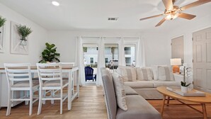 A modern living room with a sofa, chairs, a dining table, and a ceiling fan. - NEW LISTING The Proper Pelican 30A: STEPS to the BEACH! (Santa Rosa Beach)