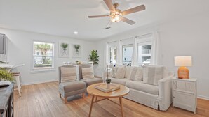 A modern living room with a sofa, chairs, a coffee table, and a ceiling fan. - NEW LISTING The Proper Pelican 30A: STEPS to the BEACH! (Santa Rosa Beach)
