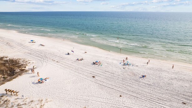 A wide sandy beach with clear blue water, umbrellas, and people. - NEW LISTING The Proper Pelican 30A: STEPS to the BEACH! (Santa Rosa Beach)