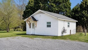 A small, single-story building with a gabled roof, a front porch, and a small window. - Private 1BR GuestHouse Near Charlotte Pet Friendly (Indian Trail)