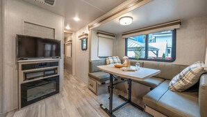 A compact RV interior with a kitchenette, a seating area, and a window providing a view of the outside.