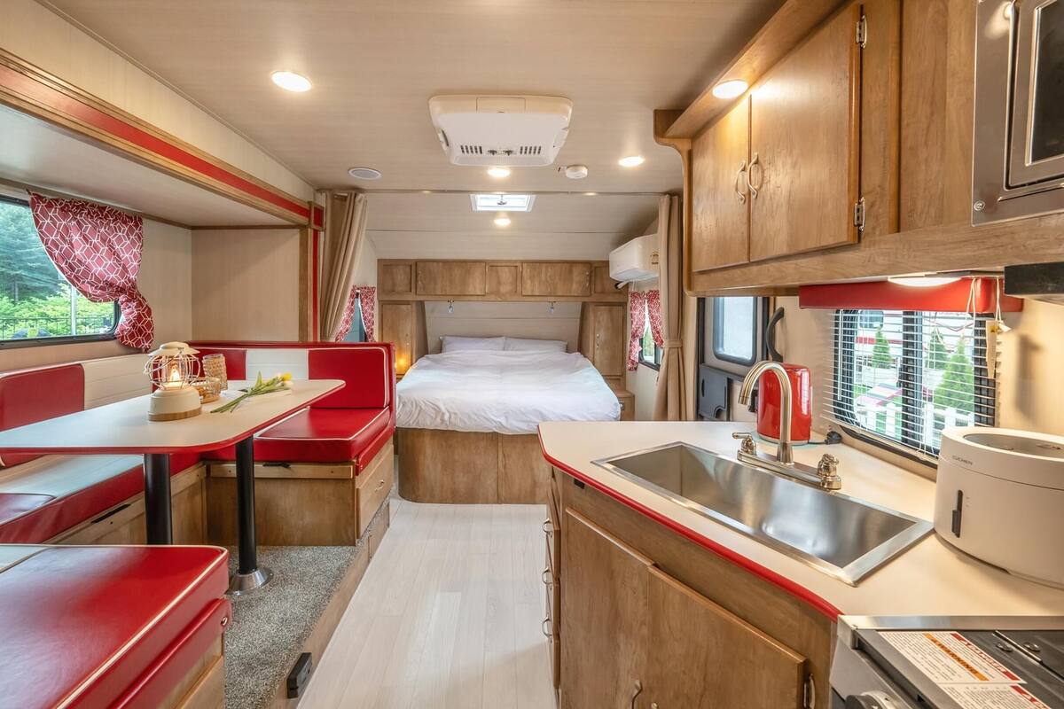 Interior compacto de autocaravana con kitchenette, zona de comedor y litera.