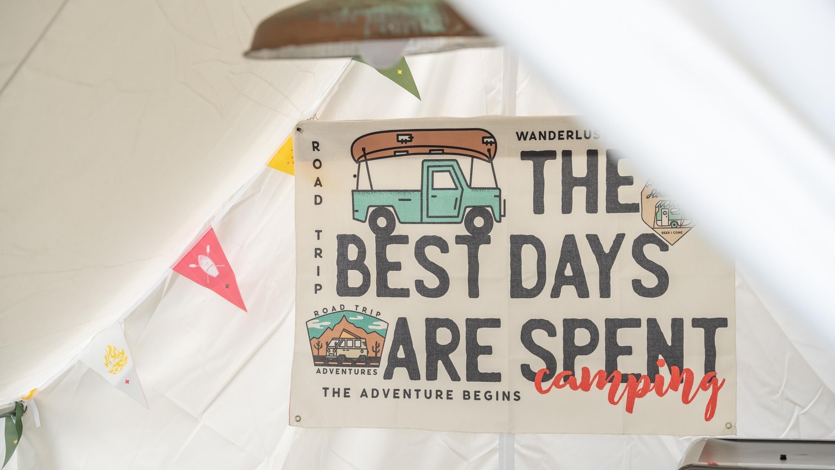 A sign with a road trip theme, featuring a camper van and the text "THE BEST DAYS ARE SPENT camping".