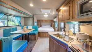 A compact RV interior with a kitchenette, a dining area, and a sleeping berth. - Gapyeong Dongban84 Glamping&pool Villa (Gapyeong)