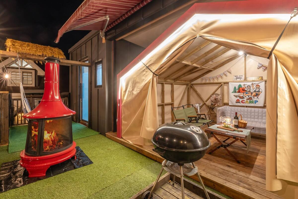 Un espacio al aire libre con carpas, una parrilla y un estufa de leña.