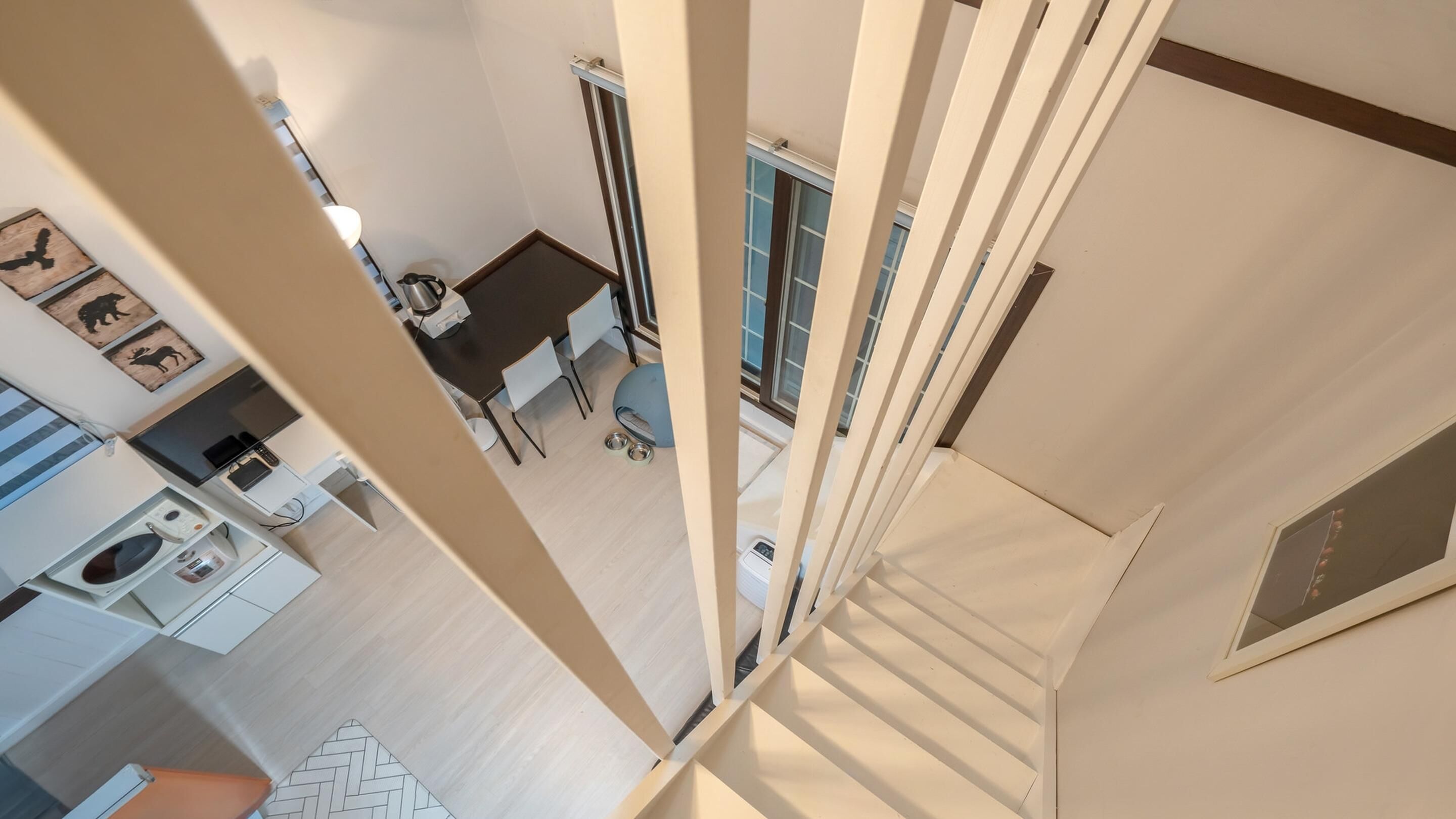 A modern kitchen with a dining area, a staircase, and a view of the living room.