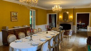 Un comedor formal con una larga mesa dispuesta para una comida, candelabros y una chimenea.