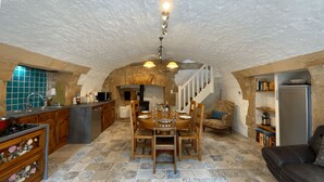 Una cocina rústica con una mesa de comedor para seis, una escalera y una sala de estar acogedora con un sofá.
