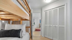 A bedroom with a bunk bed, a wardrobe with louvered doors, and a hallway leading to another room. - Golf course townhouse w/ free shuttle, parking (Whistler)