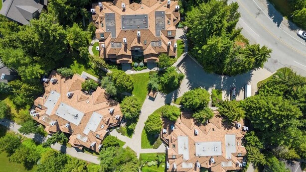 An aerial view of a residential area with multiple houses, each featuring a distinct roof design and surrounded by greenery. - Golf course townhouse w/ free shuttle, parking (Whistler)