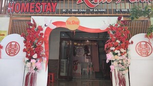 L’entrée d’un hôtel, avec une enseigne indiquant « Kim An Homestay » et des compositions florales décoratives.