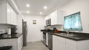 Una cocina moderna con armarios blancos, electrodomésticos de acero inoxidable y encimera de granito.