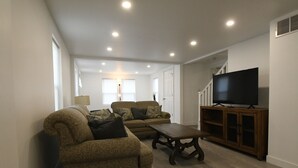 Una sala de estar con dos sofás, una mesa de centro y un televisor sobre un mueble de madera.